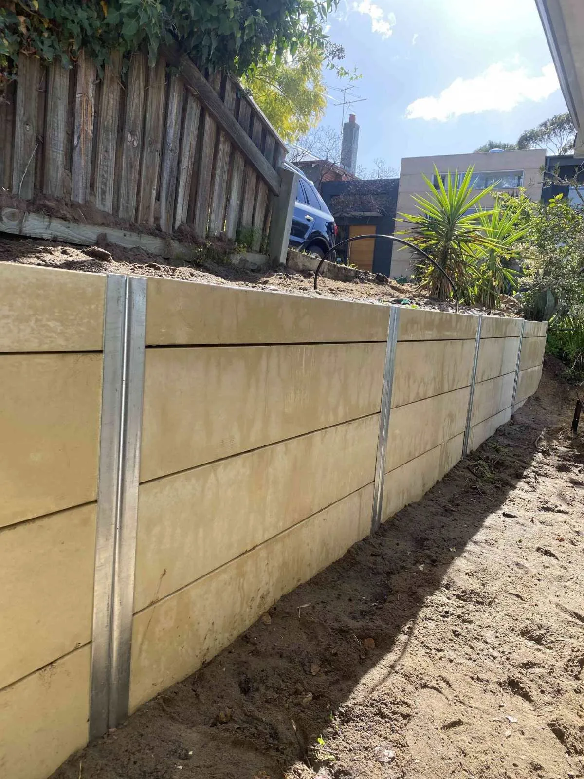 Panel retaining wall with galvanised steel posts below an old timber fence